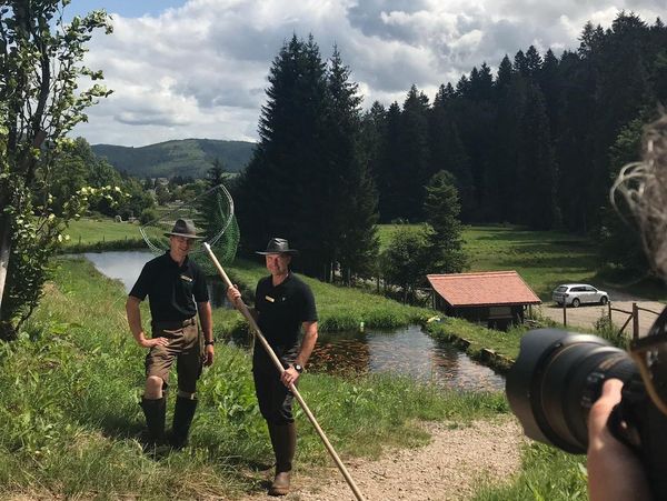 Zwei Männer mit einem großen Fischkescher vor einem kleinen Teich